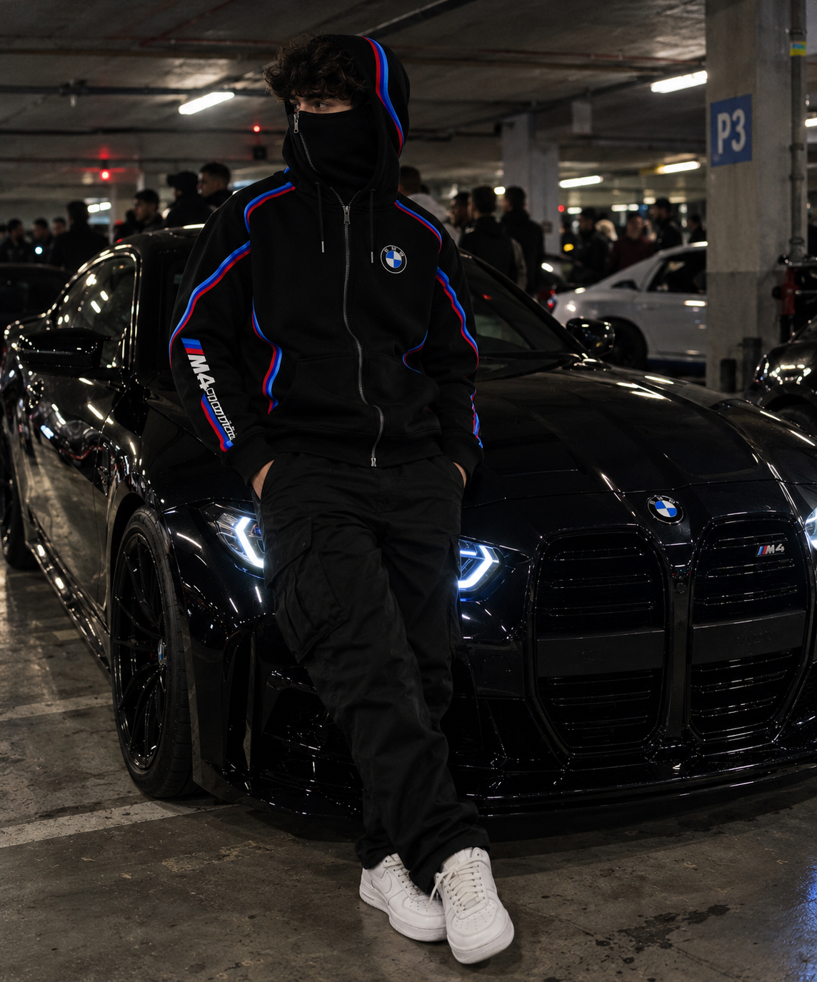 BMW design hoodie male lifestyle realistic underground car meet with integrated balaclava and black BMW M4 Competition