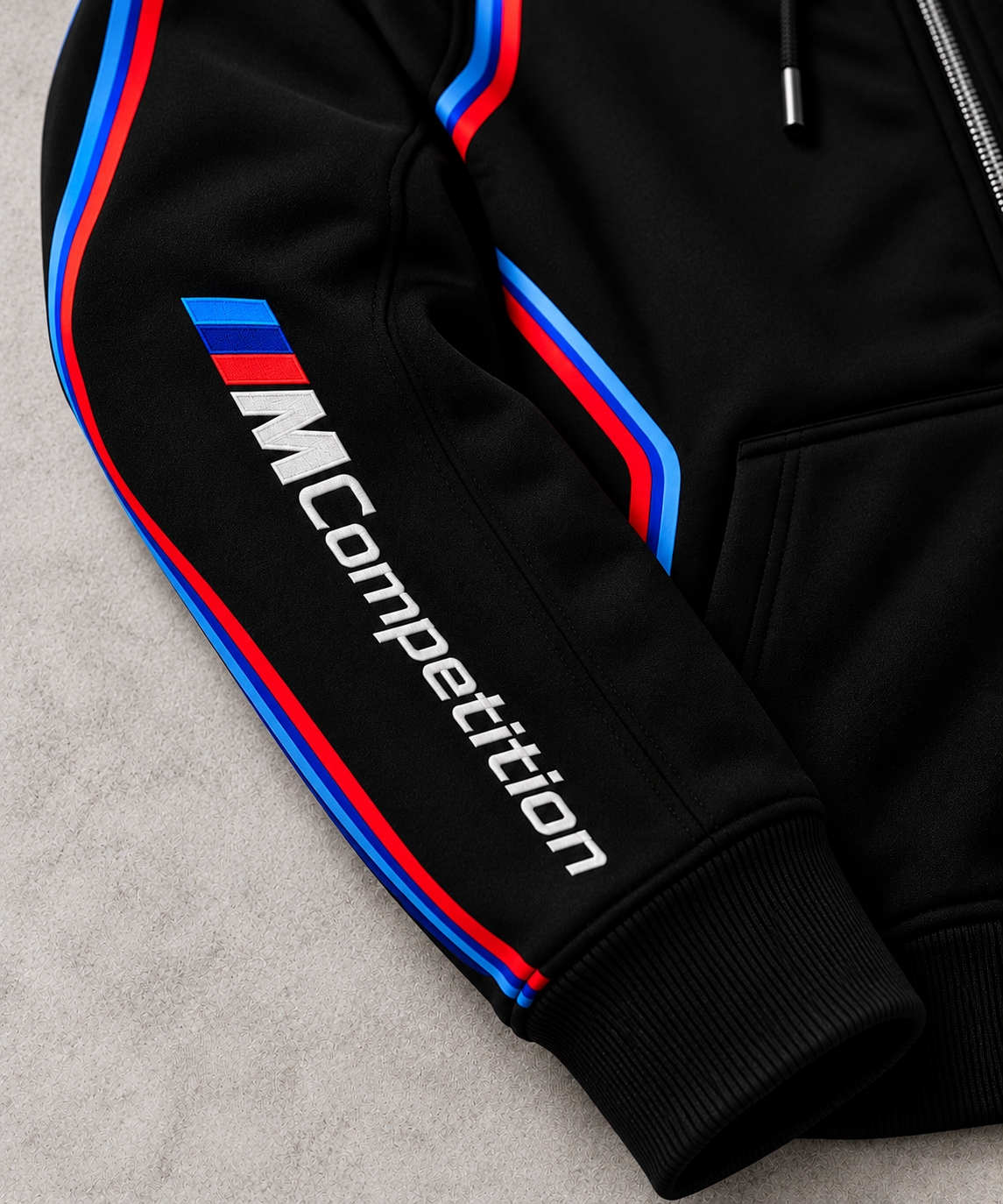 BMW design hoodie signature MCompetition right sleeve close-up with blue and red stripes on grey concrete background