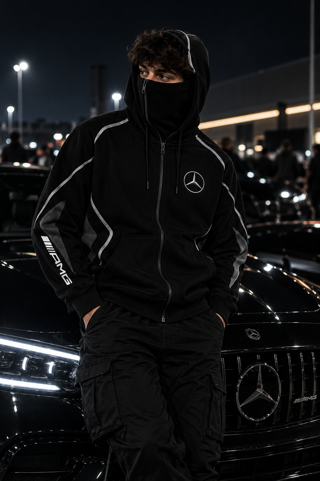 REVLINE Mercedes AMG hoodie male lifestyle photo at nighttime car meet, zip-up balaclava hood, Mercedes star chest and AMG sleeve