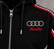 Audi RS hoodie chest logo close-up — silver Audi rings with red Audi lettering, black fabric, red and white piping