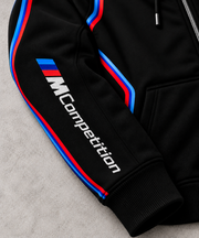 BMW design hoodie signature MCompetition right sleeve close-up with blue and red stripes on grey concrete background