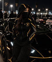 REVLINE Lamborghini female lifestyle nighttime car meet, black and gold zip-up balaclava hoodie with gold shield chest and Lamborghini sleeve script