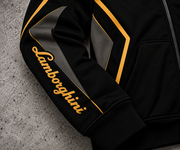 REVLINE Lamborghini hoodie sleeve close-up gold Lamborghini script, gold piping, charcoal panels on grey concrete