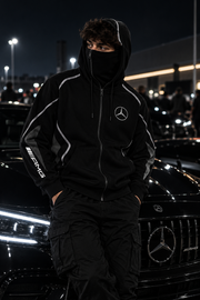 REVLINE Mercedes AMG hoodie male lifestyle photo at nighttime car meet, zip-up balaclava hood, Mercedes star chest and AMG sleeve